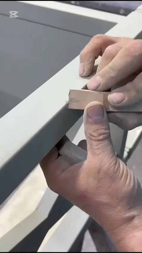 Manos lijando a mano una pieza de madera en el taller