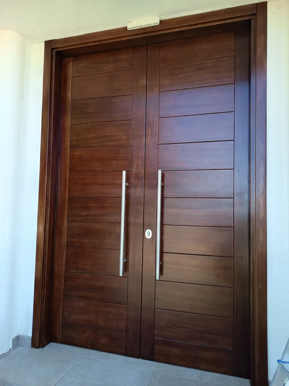 Puerta de madera maciza restaurada con tiradores de acero
